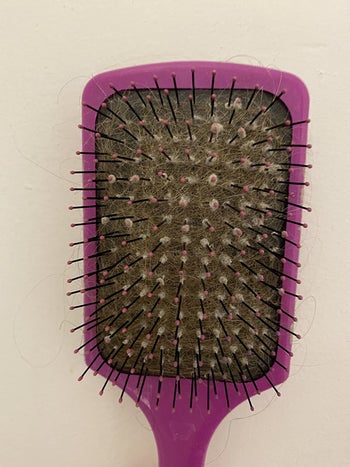 A reviewer's hairbrush caked with hair, so you can't even see the base holding the bristles