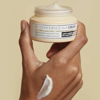 Model holding open jar of It Cosmetics Confidence In A Cream