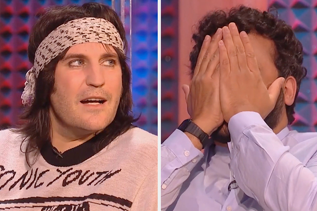 Noel Fielding looks off at someone wearing a white sweater in a TV studio and Nish Kapoor clasps his hands over his face in laughter