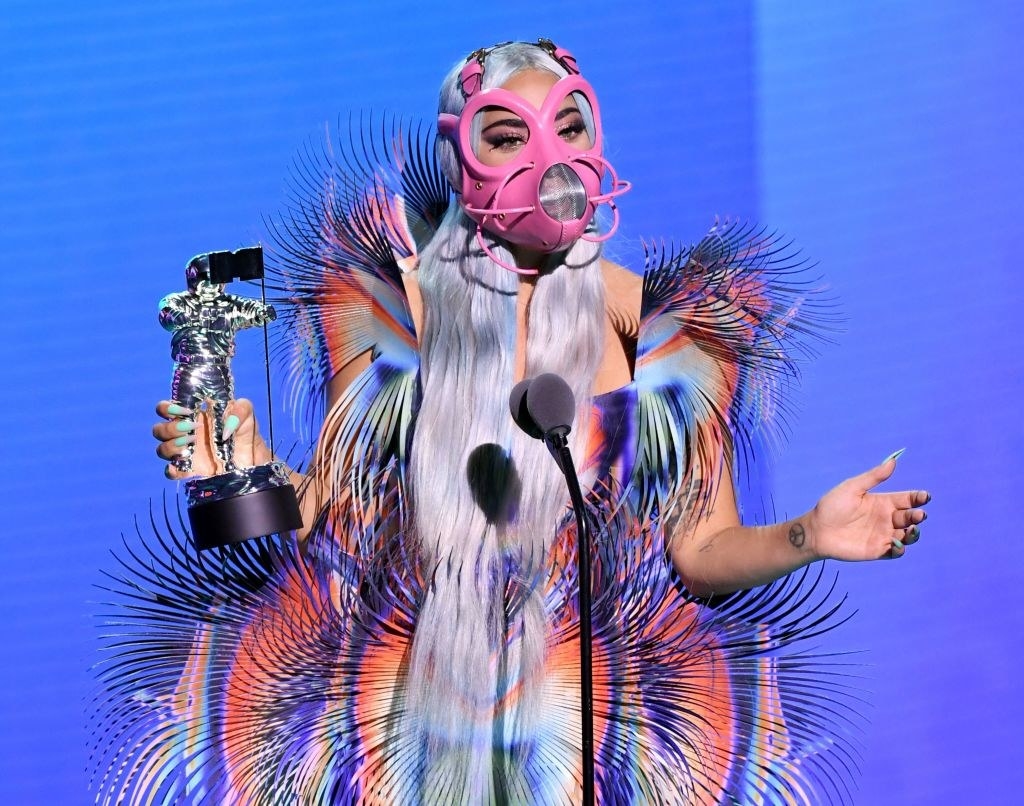 Lady Gaga at the mic wearing a bright costume giving her acceptance speech at the 2020 MTV VMAs