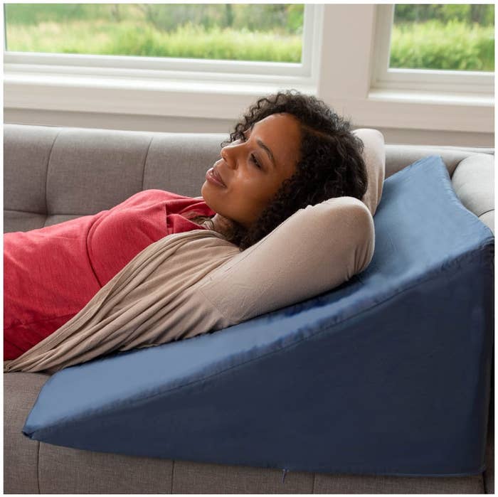 A person using the pillow while lying on a couch