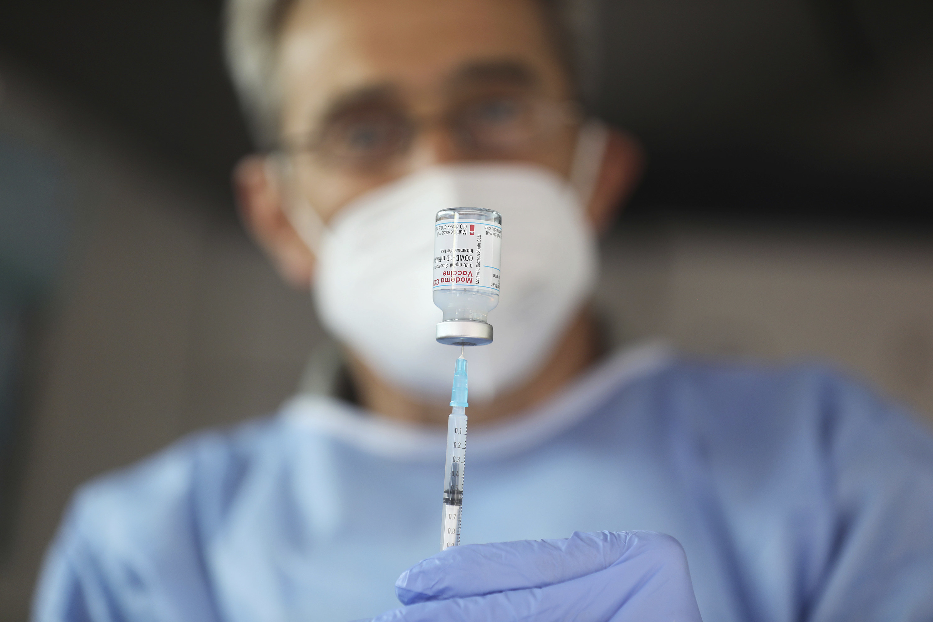 Healthcare worker fills syringe from a vial of Moderna's COVID vaccine