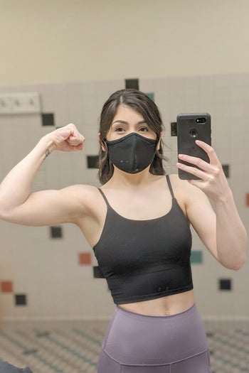 reviewer wearing the top in black and flexing while taking a selfie