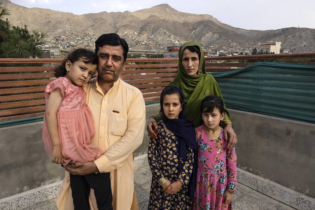 A father holds his daughter, and a mother stands with her two daughters on a rooftop in Afghanistan