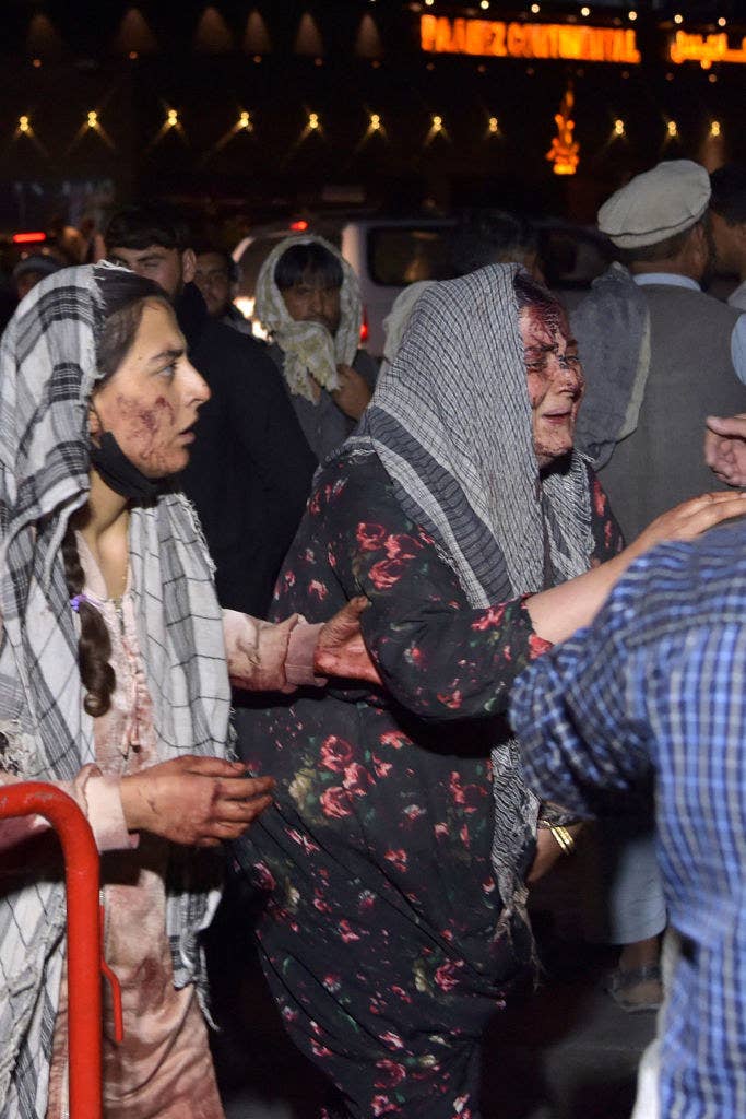 Two women in a crowd have bloody, bruised faces