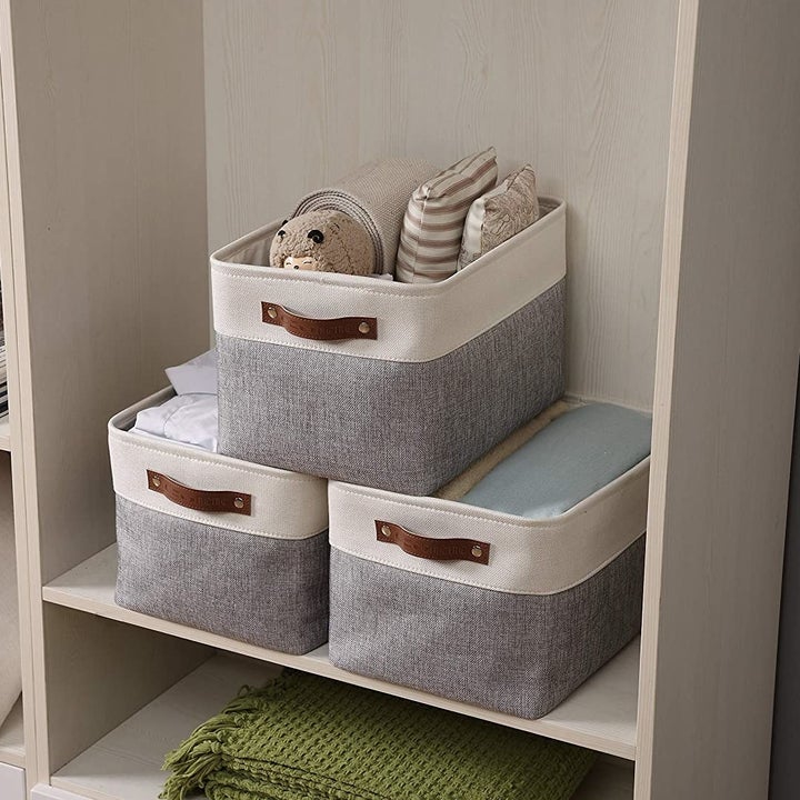 a stack of three gray and cream bins with leather handles 