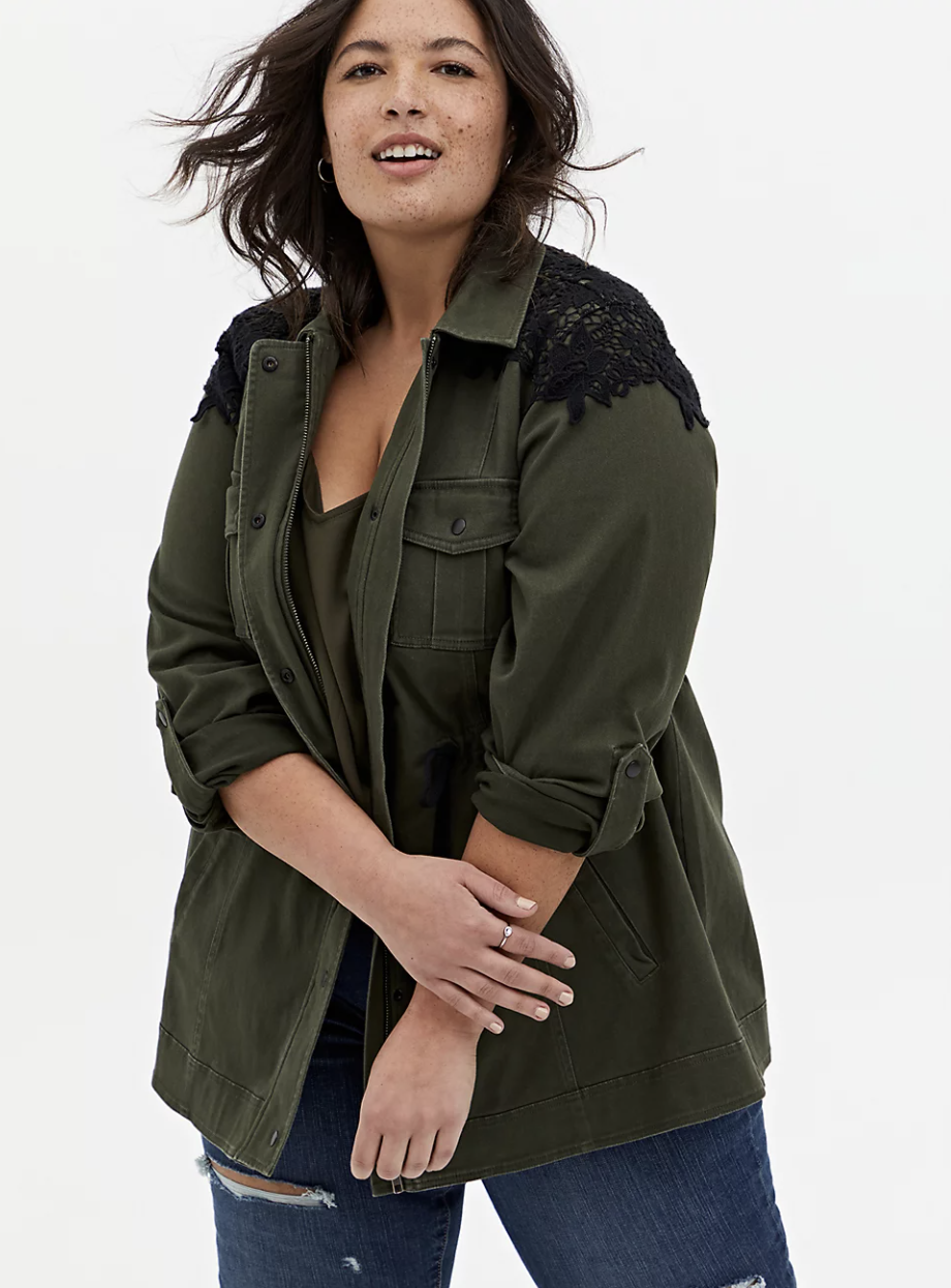 Model in green zip up anorak with sleeves rolled up and held in place with buttons