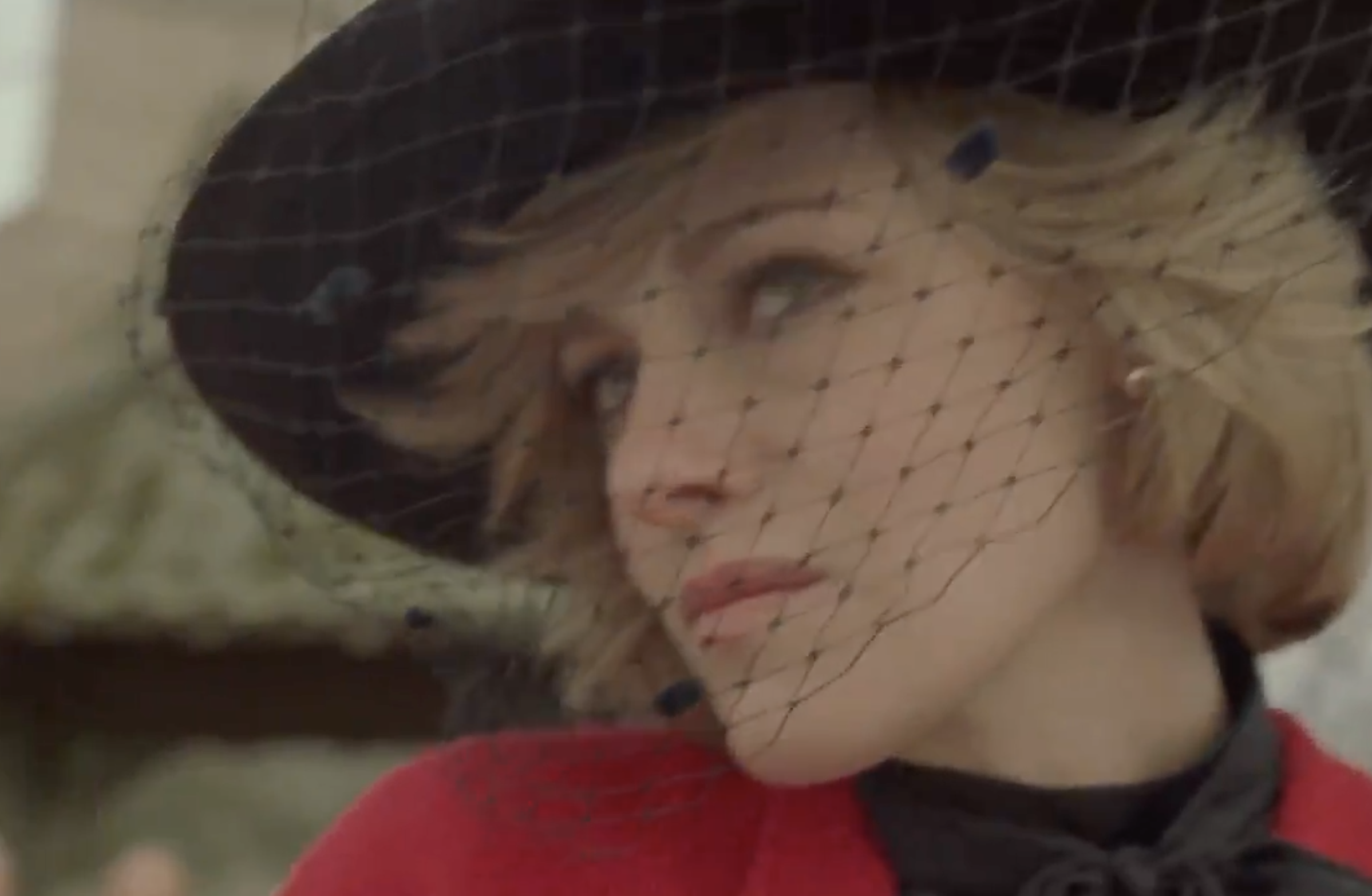 Kristen as Diana wearing a wide-brim black hat with birdcage veil