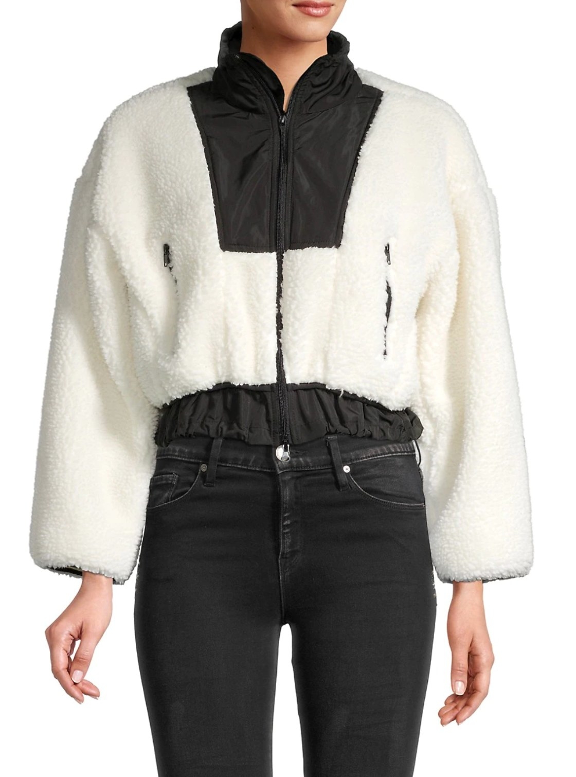 model wearing the white furry bomber with black detailing at the neck and waist and black jeans to match