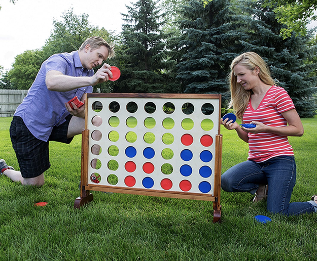 Models play with a giant 4 Connect game in their backyard