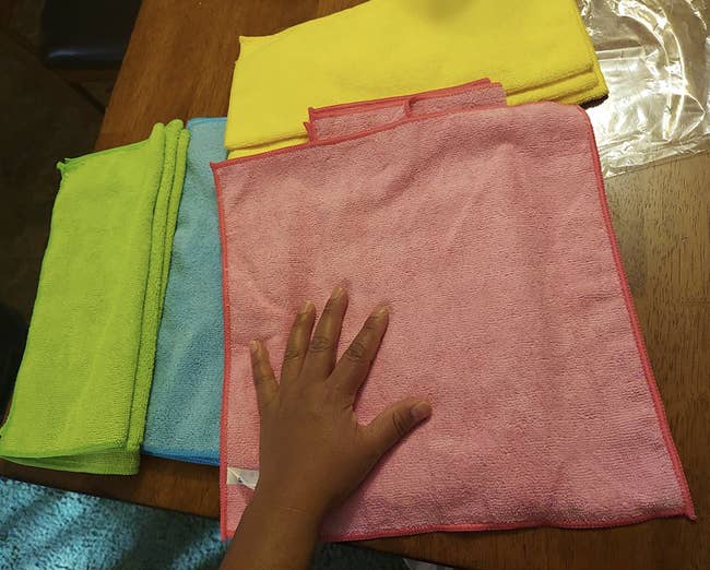 Reviewer showing large size of square shaped towels in pink, green, yellow, and blue