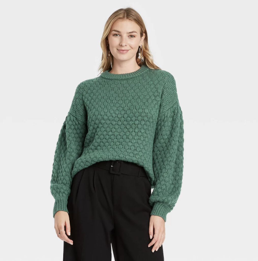 a model in a green sweater with a circle pattern on it and balloon sleeves