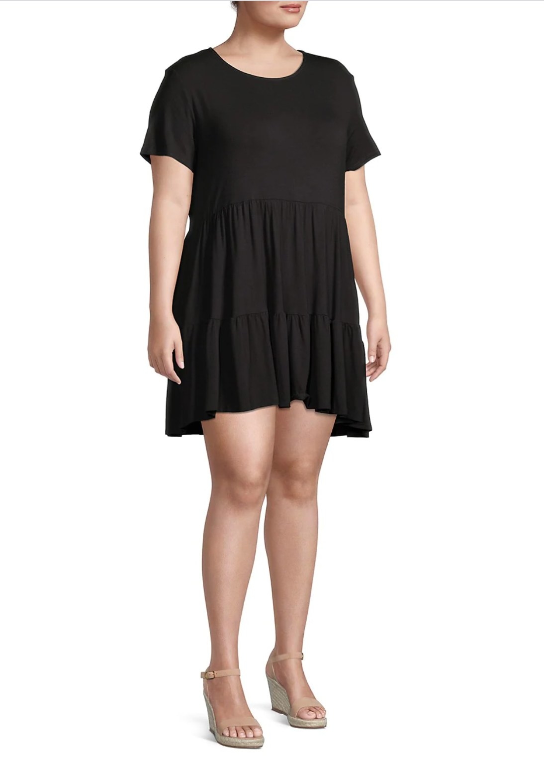 model wearing the black dress with ruffles that ends at the mid thigh with tan wedges