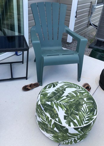 a reviewer photo of a patio chair with a palm-printed inflatable ottoman in front to it 