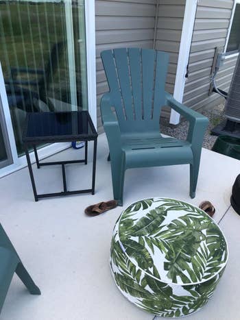 a reviewer photo of a patio chair with a palm-printed inflatable ottoman in front to it 