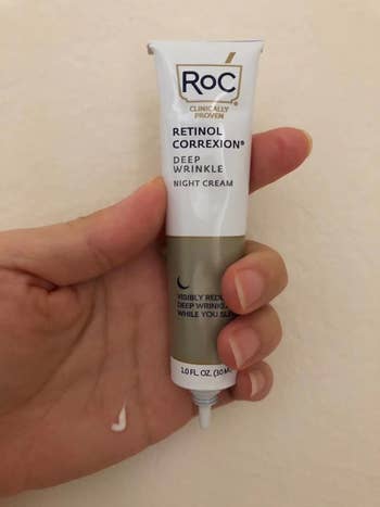 Reviewer holding tube of Roc Retinol night cream