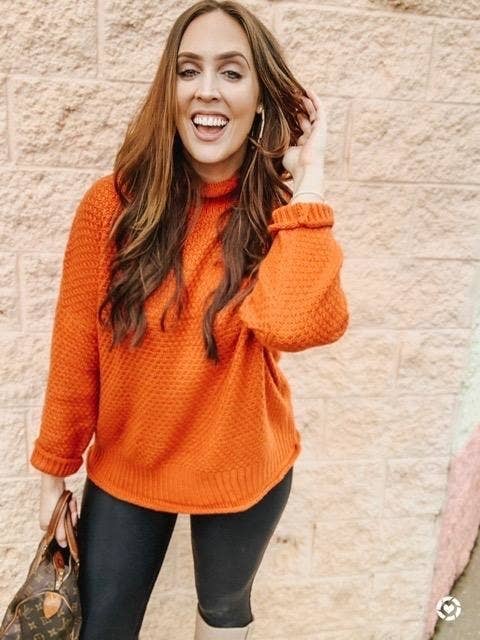 Reviewer photo of a person wearing an orange mock neck sweater with black leggings