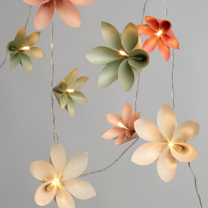several origami flowers on a string with small lights in the center of each