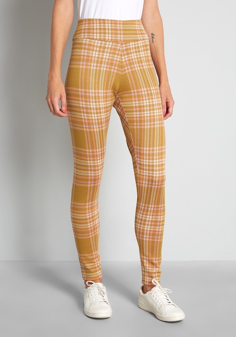 Model is wearing mustard yellow plaid pants with white shoes