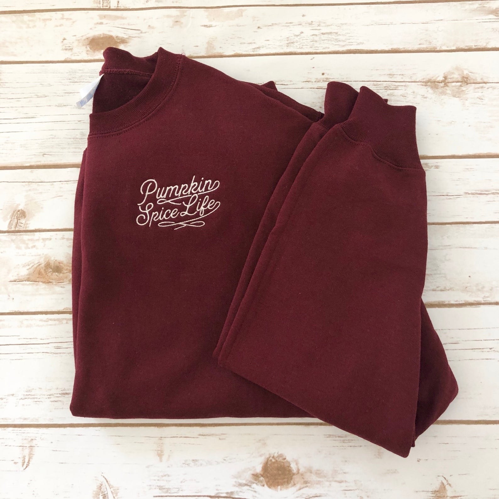 a maroon colored sweatshirt with white embroidery that says pumpkin spice life on it