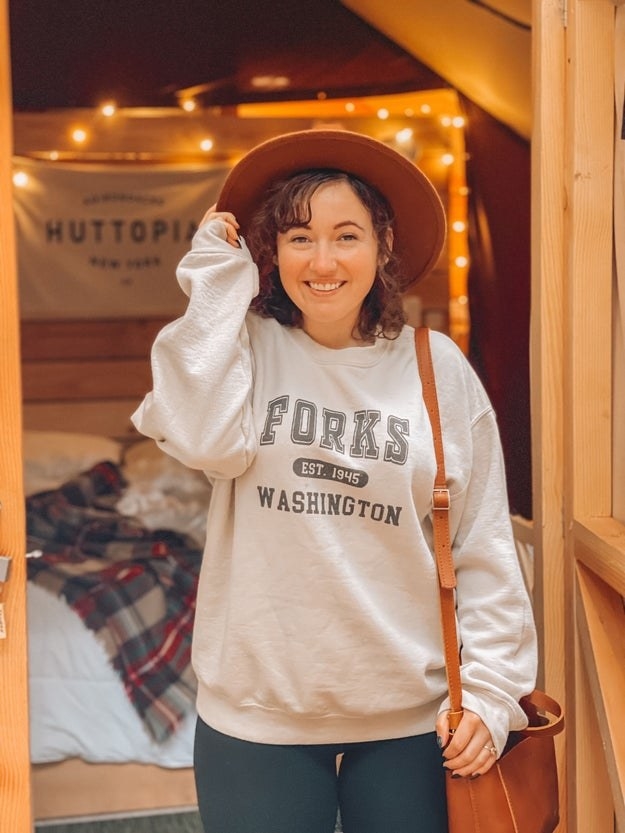 The staff writer is wearing a cream sweatshirt that says &quot;Forks, Washington Establish 1945&quot; and black leggings