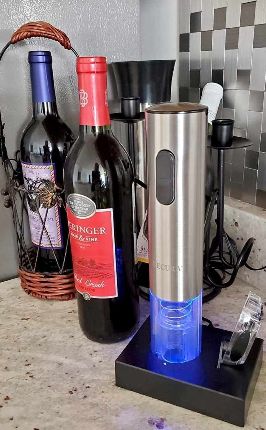 a reviewer photo of the electric corkscrew sitting on its charging dock next to the included foil cutter 