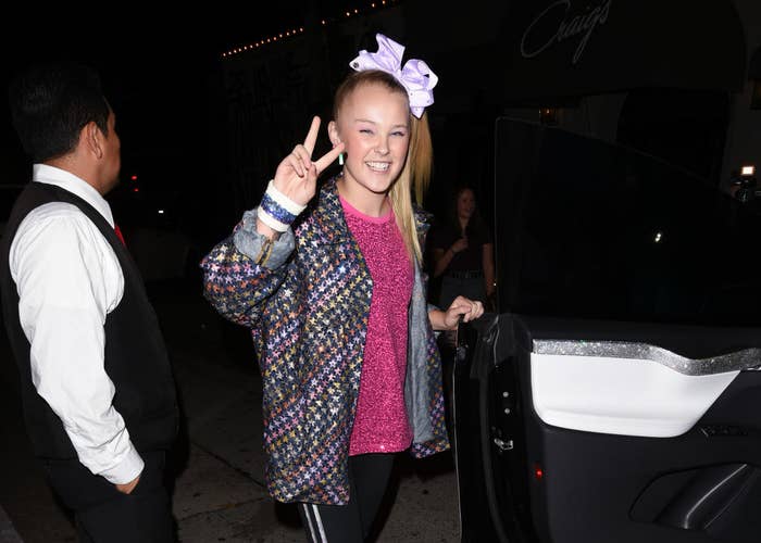 JoJo Siwa smiling giving the peace sign before entering a car