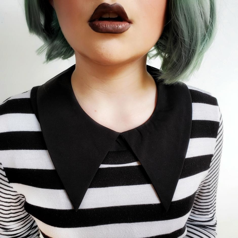 Model is wearing a white and black striped top with a black removable fang collar