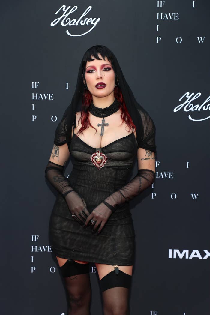 Halsey on the red carpet in a short dark dress, matching gloves, a veil and stockings