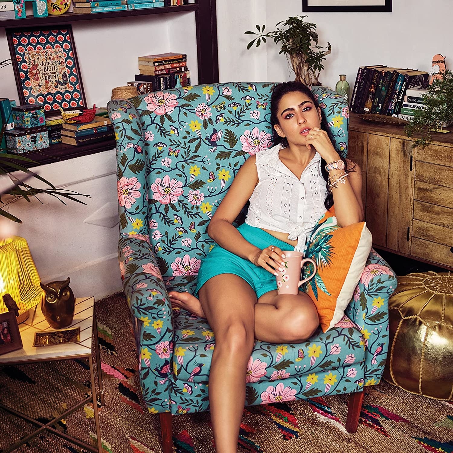 Sara Ali Khan sitting on a light blue wing chair with a floral design. amzn...
