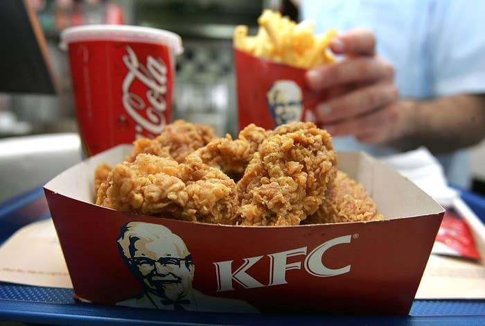 A bucket of KFC chicken, bag of fries, and a large cup of Coca-Cola