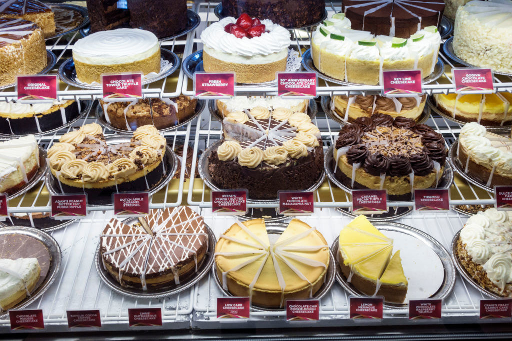 A display of many cakes and other desserts, including cheesecake