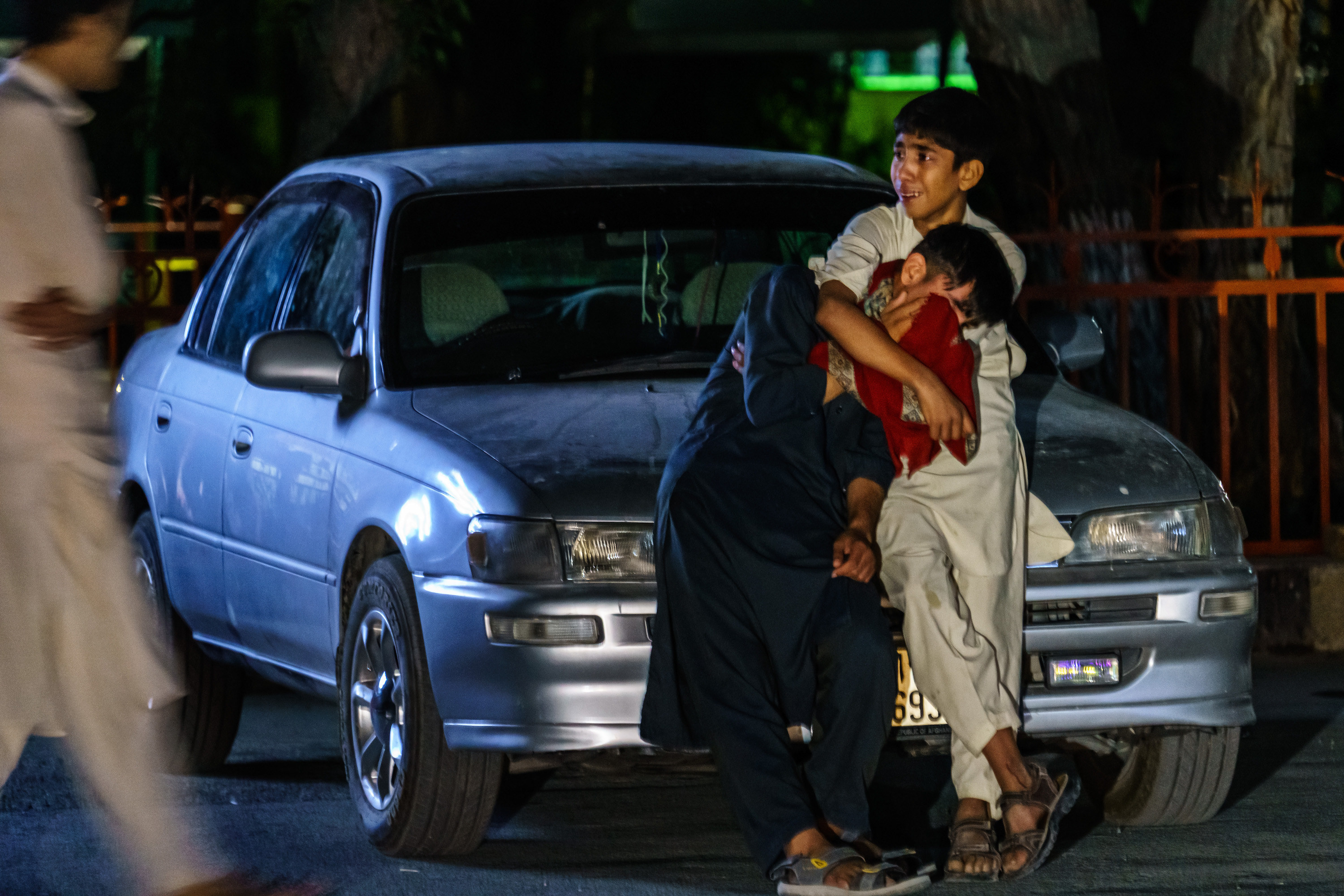 Two young Afghan boys, both weeping, hold each other
