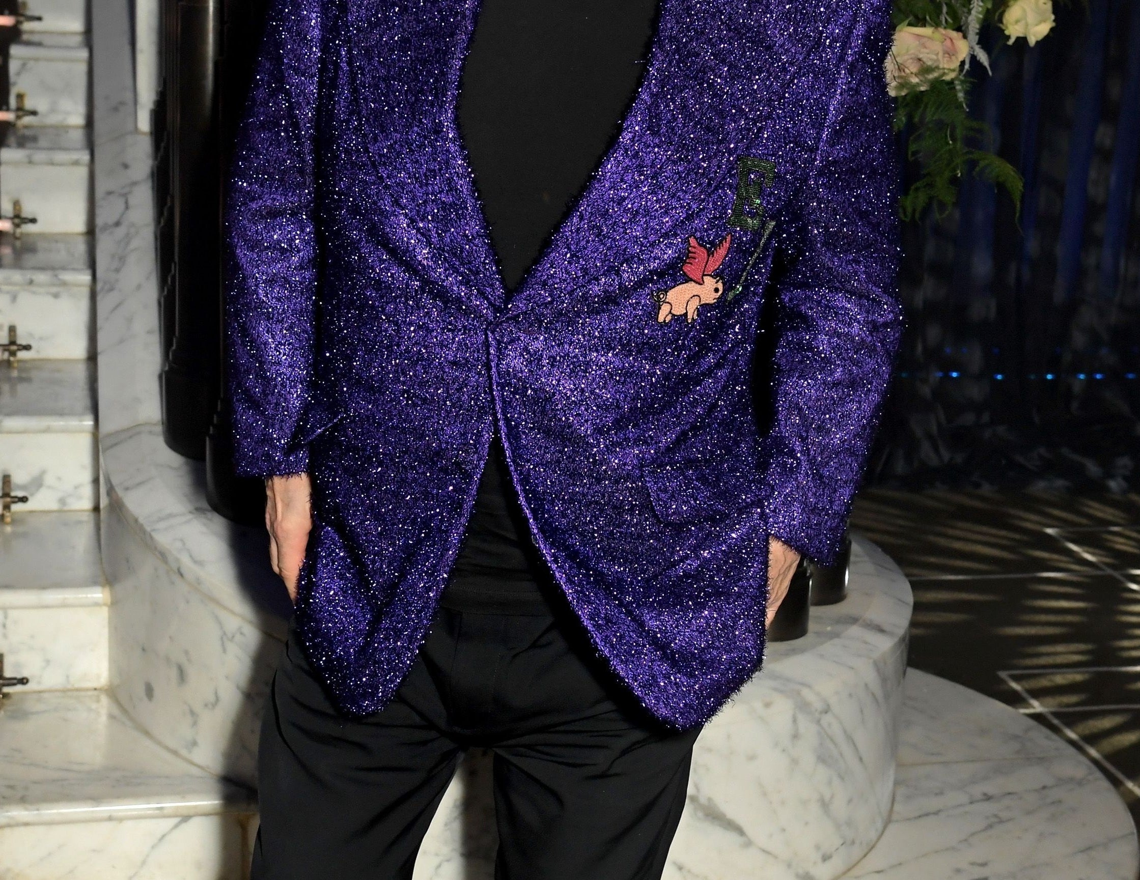 Elton wears a purple sparkly blazer and red tinted glasses