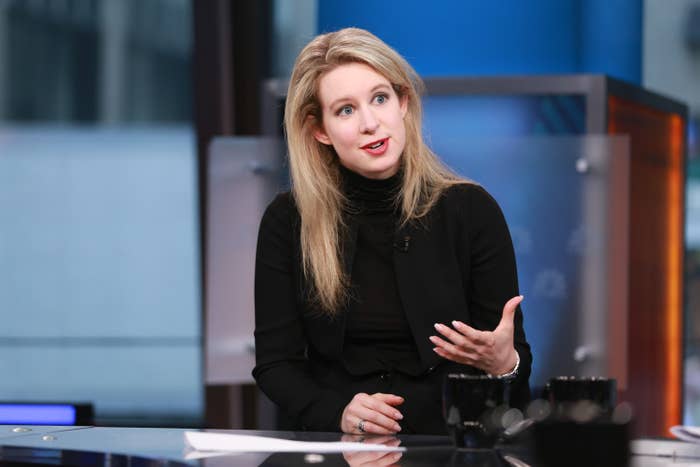 Elizabeth in her trademark black turtleneck sits at a desk