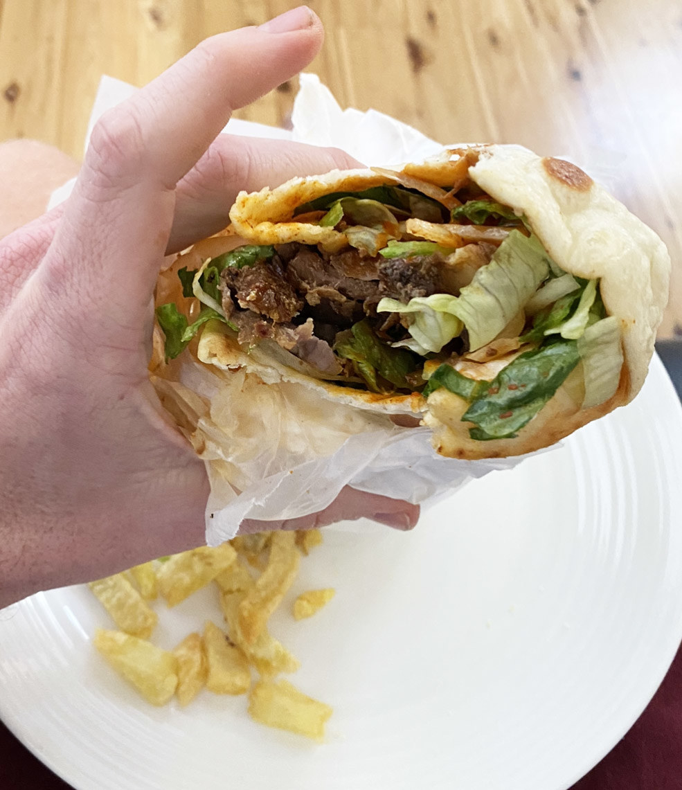 A hand holding a half-eaten kebab