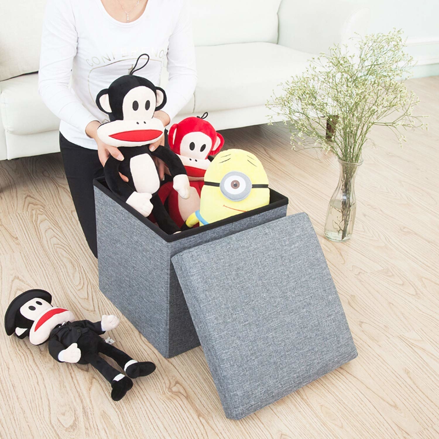 A person putting toys inside the ottoman