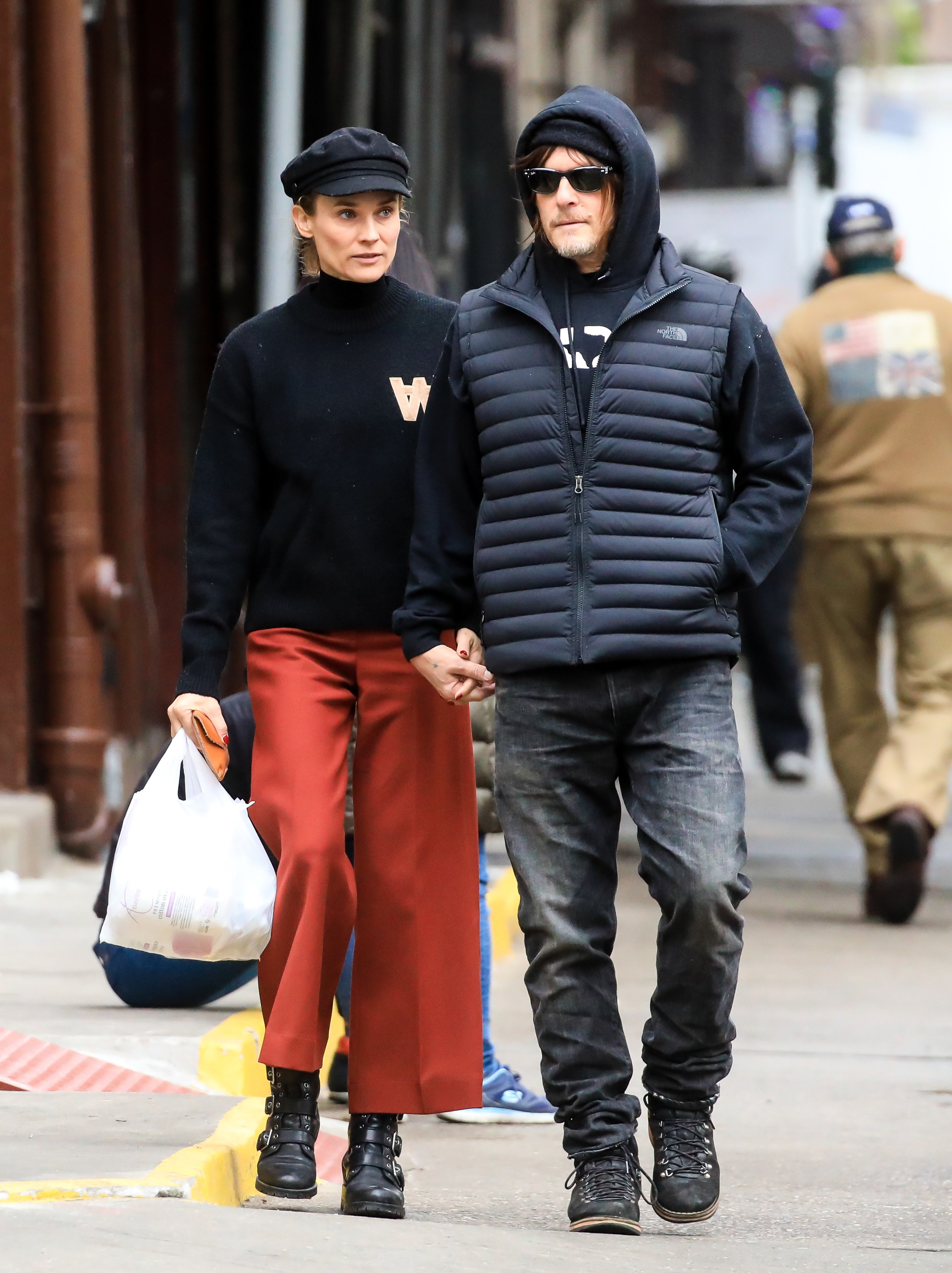 Kruger and Reedus walk down the street while Kruger holds a plastic bag in her hand
