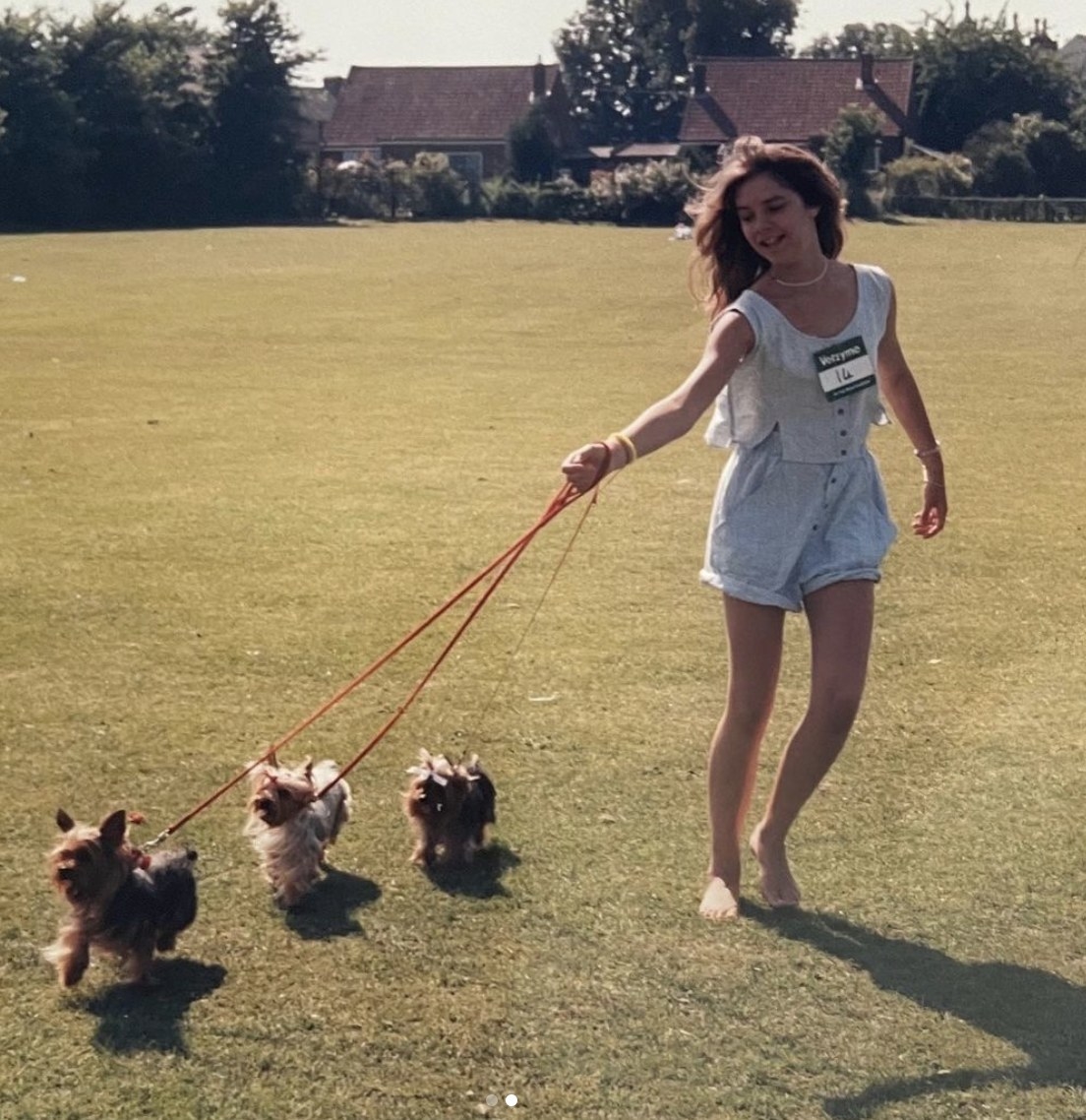 Young Victoria wears a romper and walks three dogs on a leash in a dog show