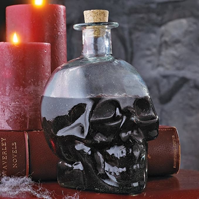 A skull shaped decanter with a drink in it
