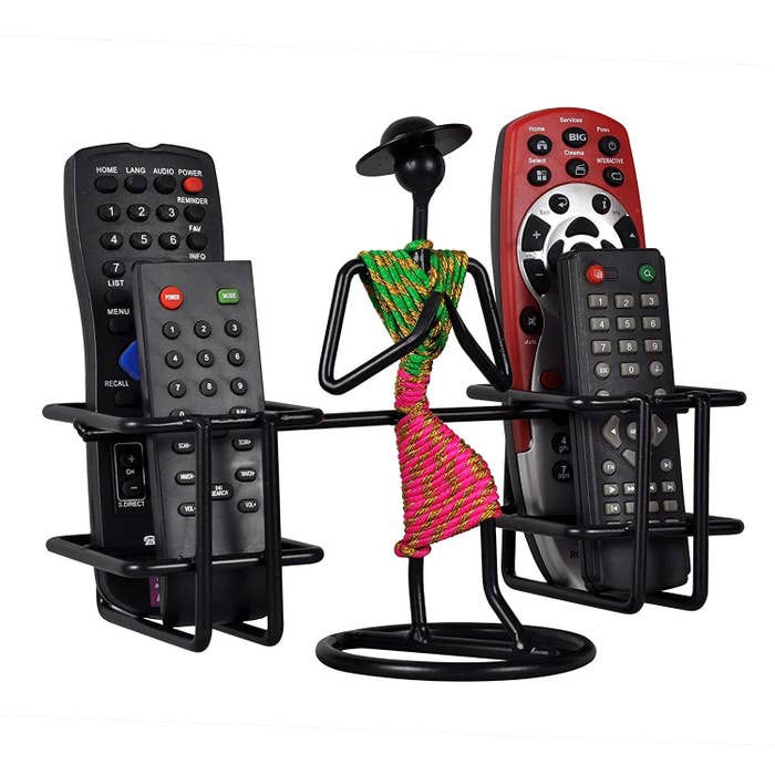 A metal remote holder with a metal lady in the middle in green and pink folding her hands