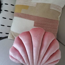 a reviewer's pink shell pillow on a couch