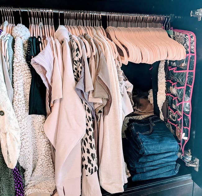 A reviewer's closet filled with clothes hanging from light pink Velvet Hangers