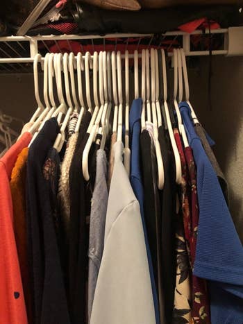reviewer showing all their plastic hangers taking up space on their clothes rack