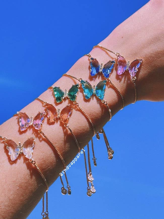 an arm with a stack of butterfly bracelets on it