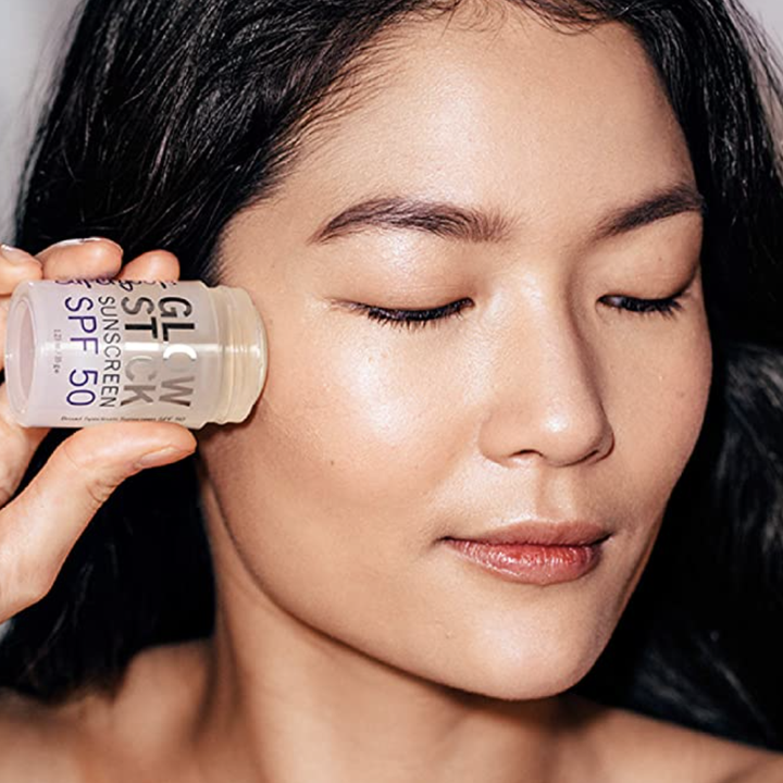 person applying glow stick to cheeks