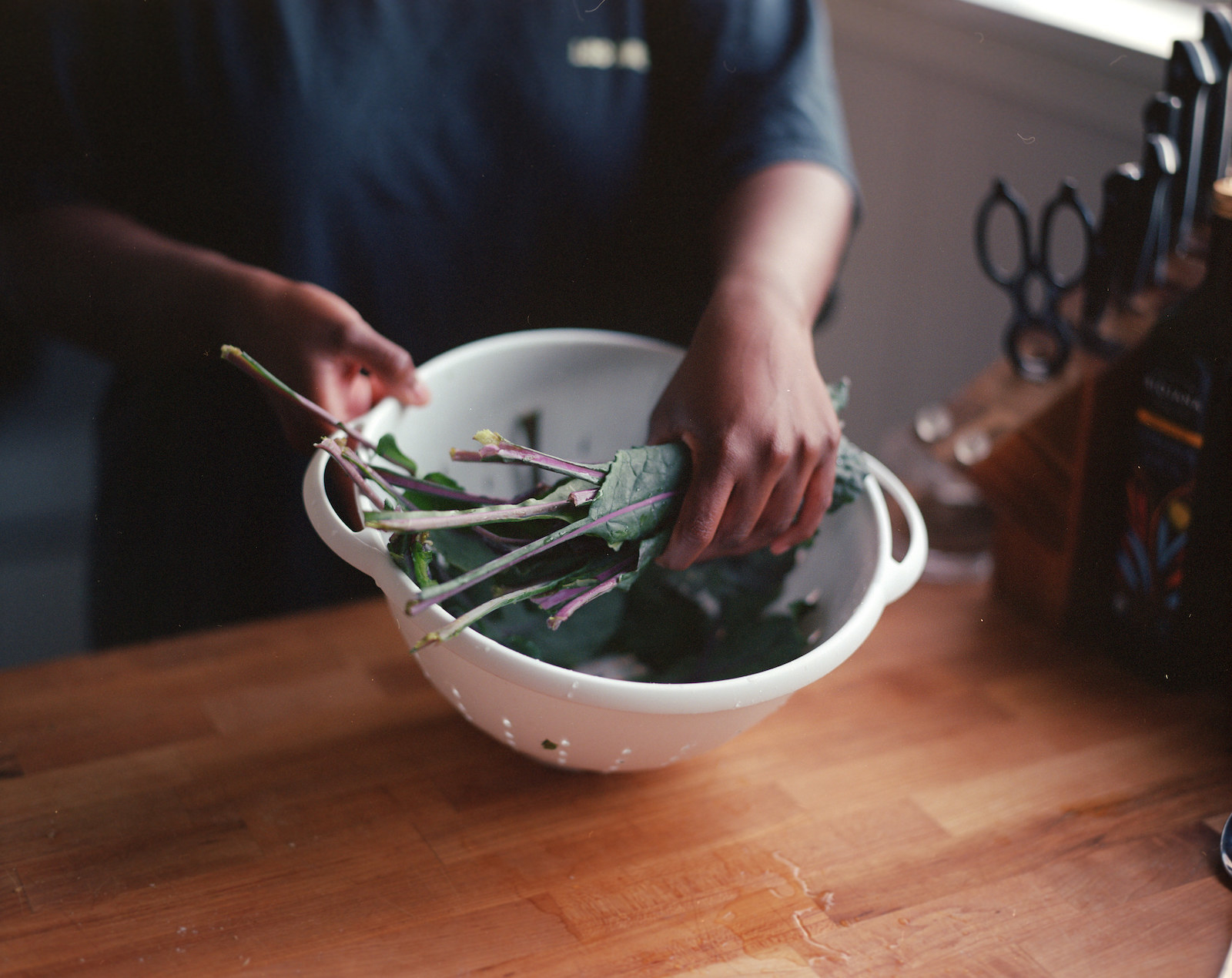 Two hands holding a colander with kale 