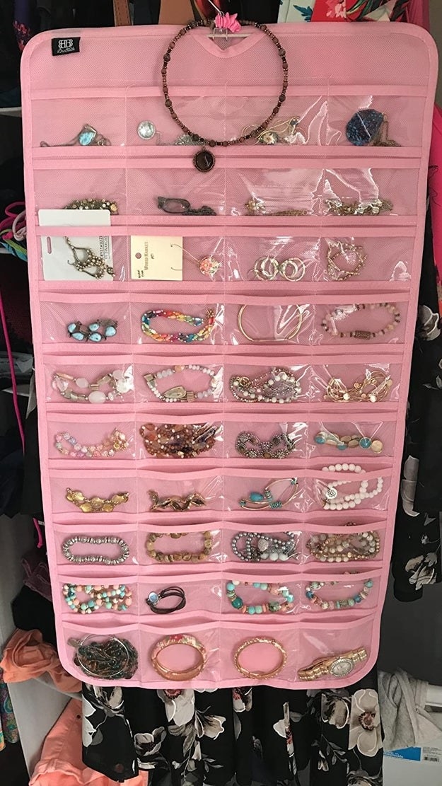 reviewer&#x27;s pink hanging jewelry organizer hanging up in a closet