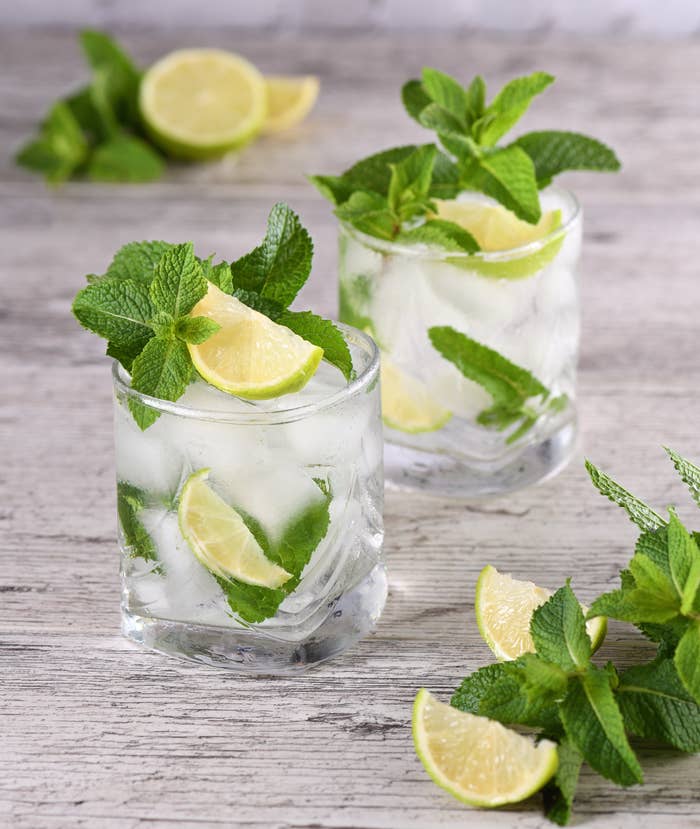 Two mojitos topped with fresh lime and lots of mint