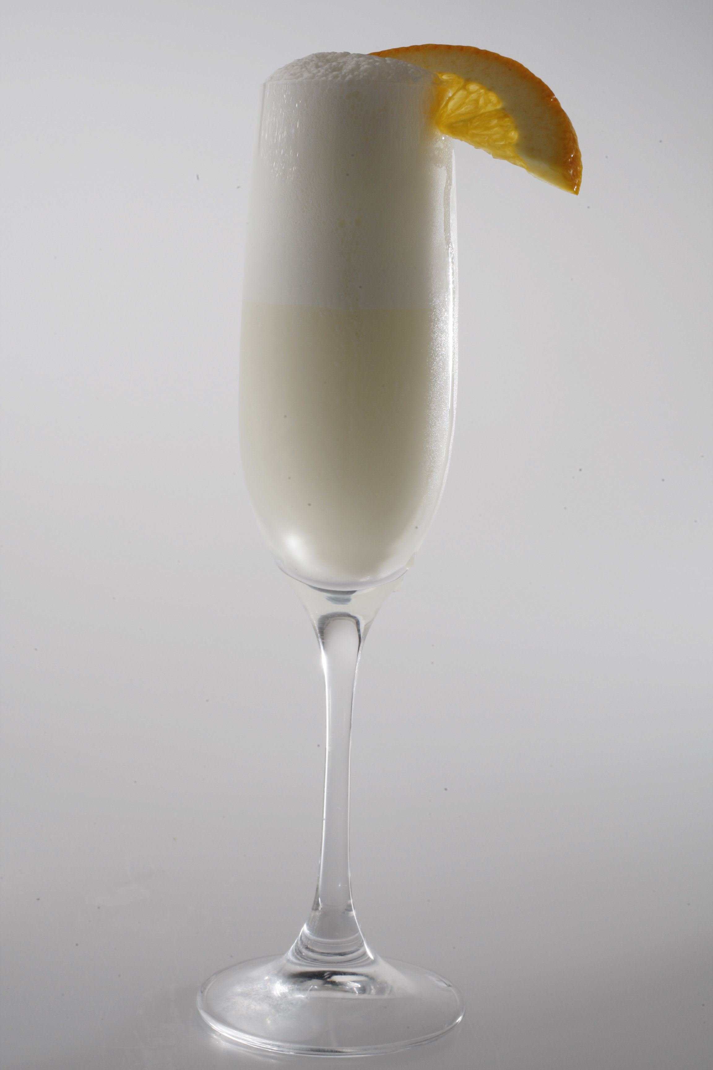 Ramos Fizz cocktail in a champagne glass garnished with orange slice